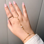 Hand wearing multiple gold bracelets on a neutral background