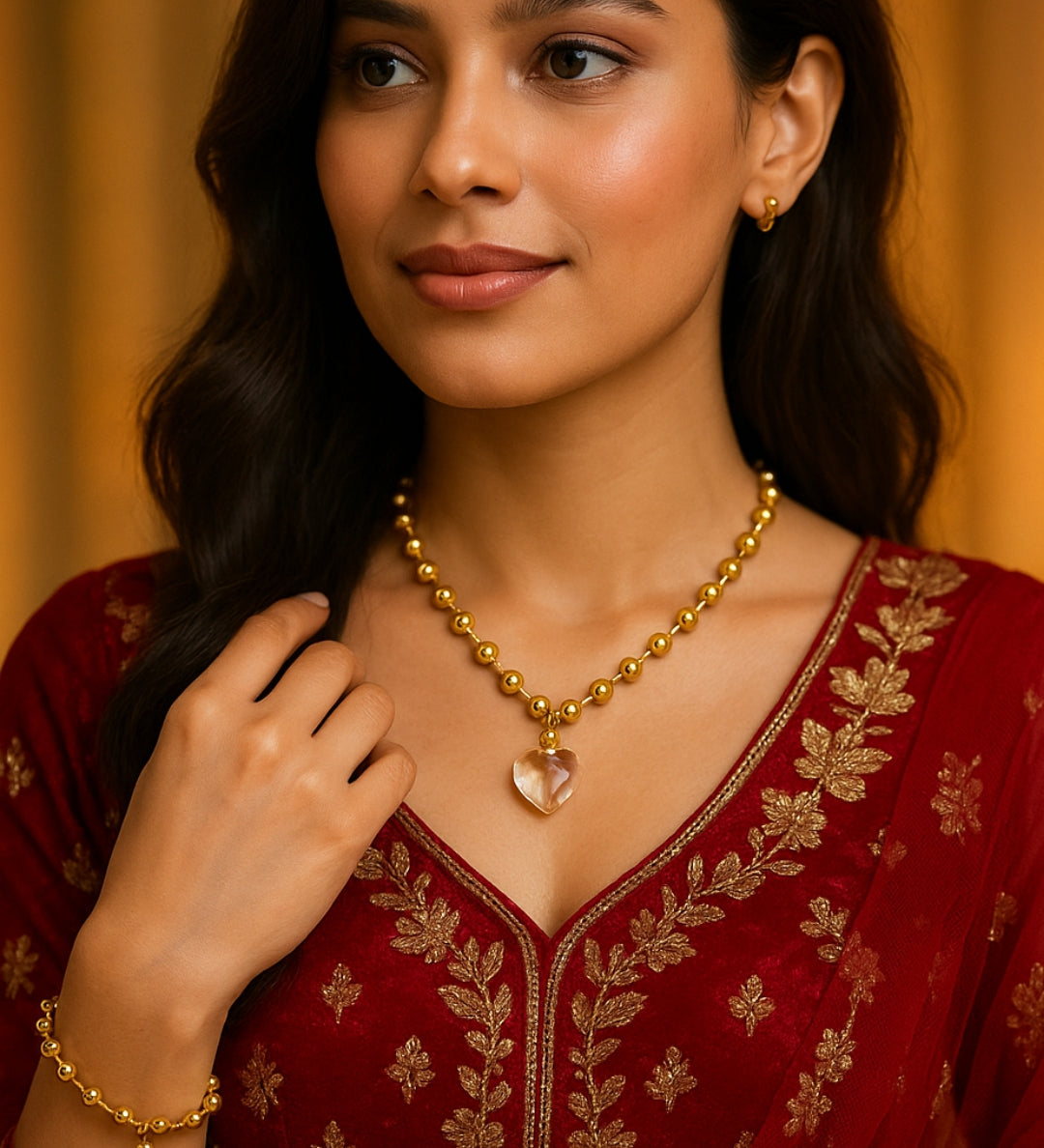 Woman wearing a gold necklace with a heart pendant on a red embroidered outfit.