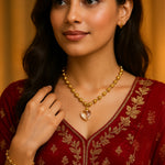 Woman wearing a gold necklace with a heart pendant on a red embroidered outfit.
