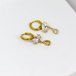 These earrings exude elegance with their dangling marquise and teardrop-shaped stones set in a golden frame
