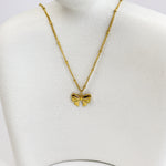 Gold bow-shaped necklace on a mannequin bust against a white background