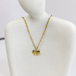 Gold bow-shaped necklace on a mannequin bust against a white background