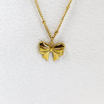 Gold bow-shaped pendant on a gold chain against a white background