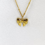 Gold bow-shaped pendant on a gold chain against a white background