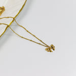 Gold necklace with a Ribbon bow pendant on a white background