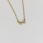 Minimalist bow necklace featuring twin heart-cut stones set in a polished gold frame on a fine link chain.