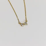 Minimalist bow necklace featuring twin heart-cut stones set in a polished gold frame on a fine link chain.