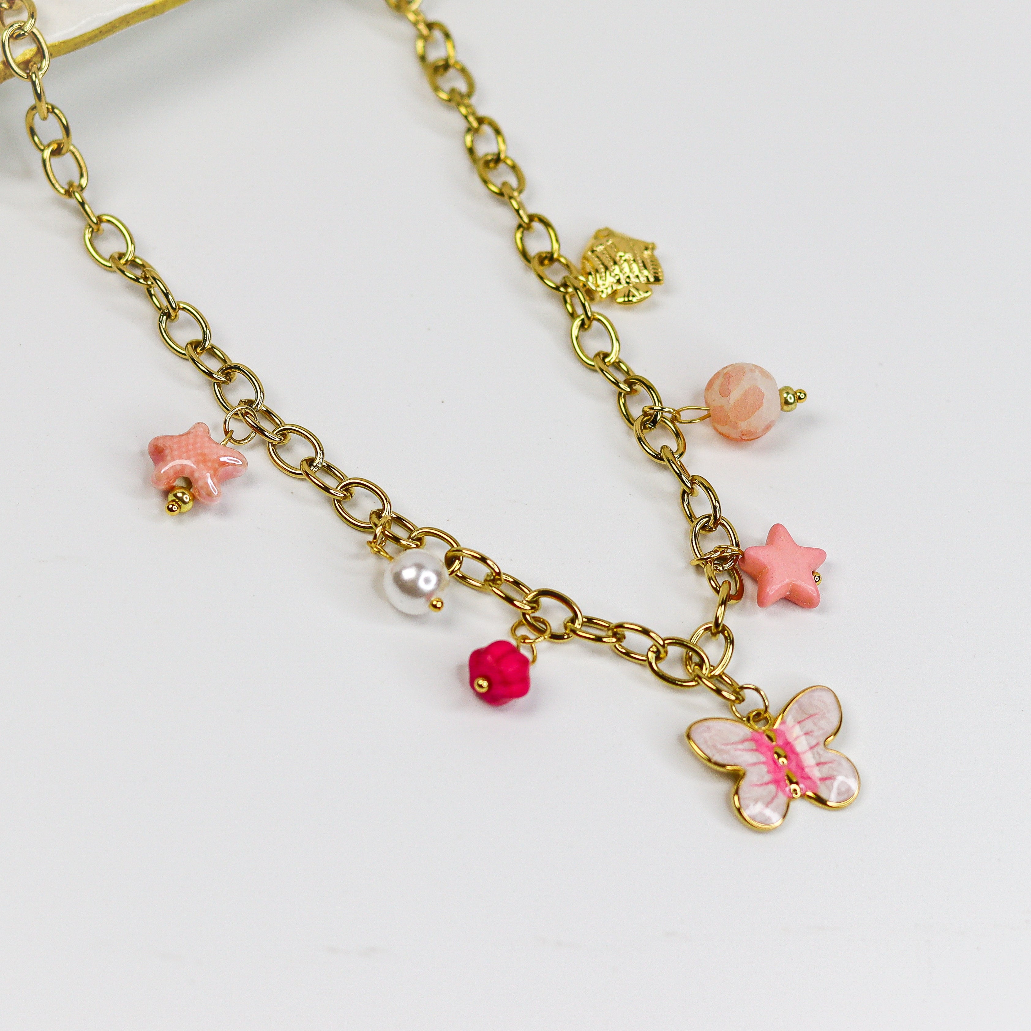 Gold-tone chunky chain adorned with a pastel butterfly, starfish, and bead charms in soft pinks and pearls.