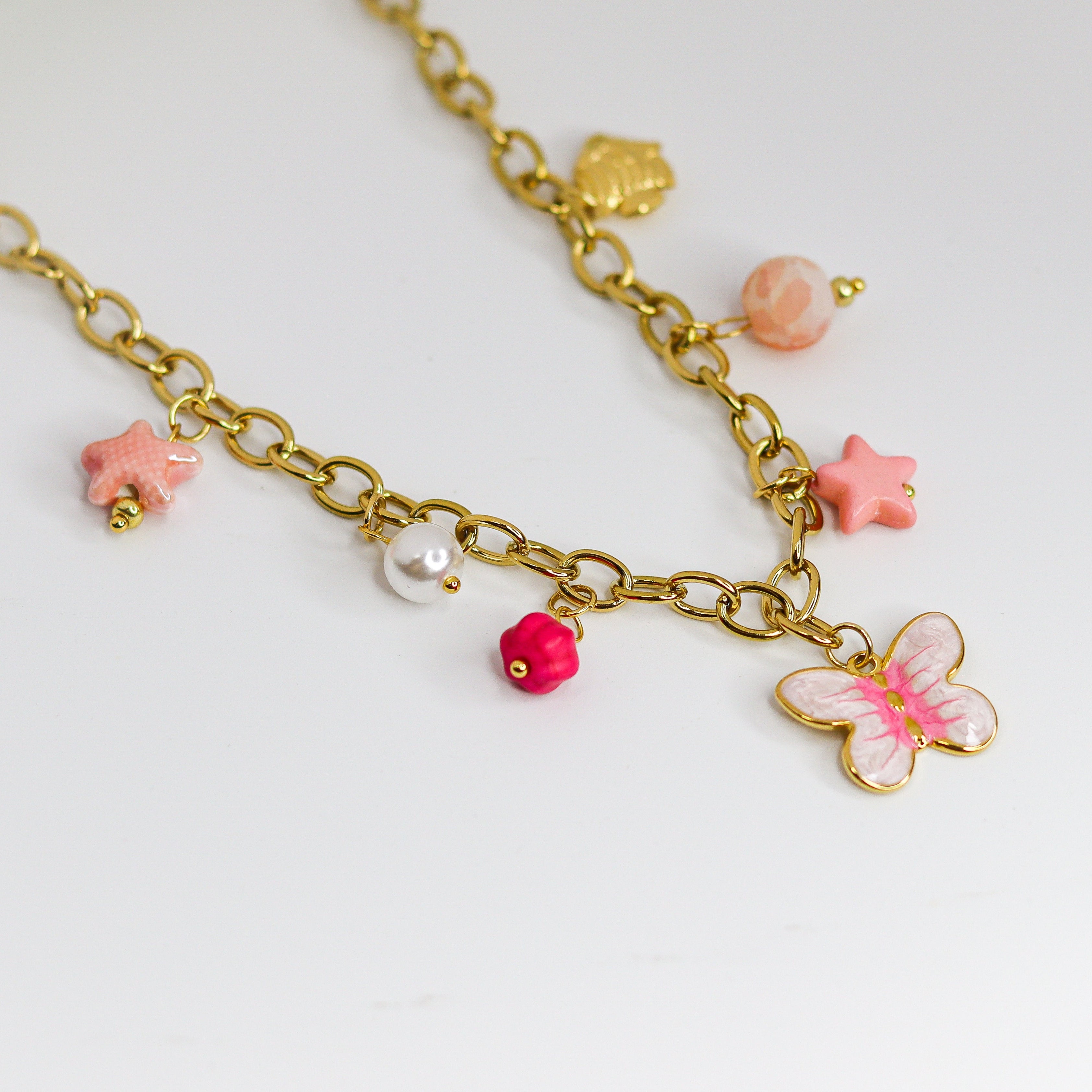 Gold-tone chunky chain adorned with a pastel butterfly, starfish, and bead charms in soft pinks and pearls.