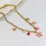 Gold-tone chunky chain adorned with a pastel butterfly, starfish, and bead charms in soft pinks and pearls.