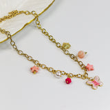 Gold-tone chunky chain adorned with a pastel butterfly, starfish, and bead charms in soft pinks and pearls.