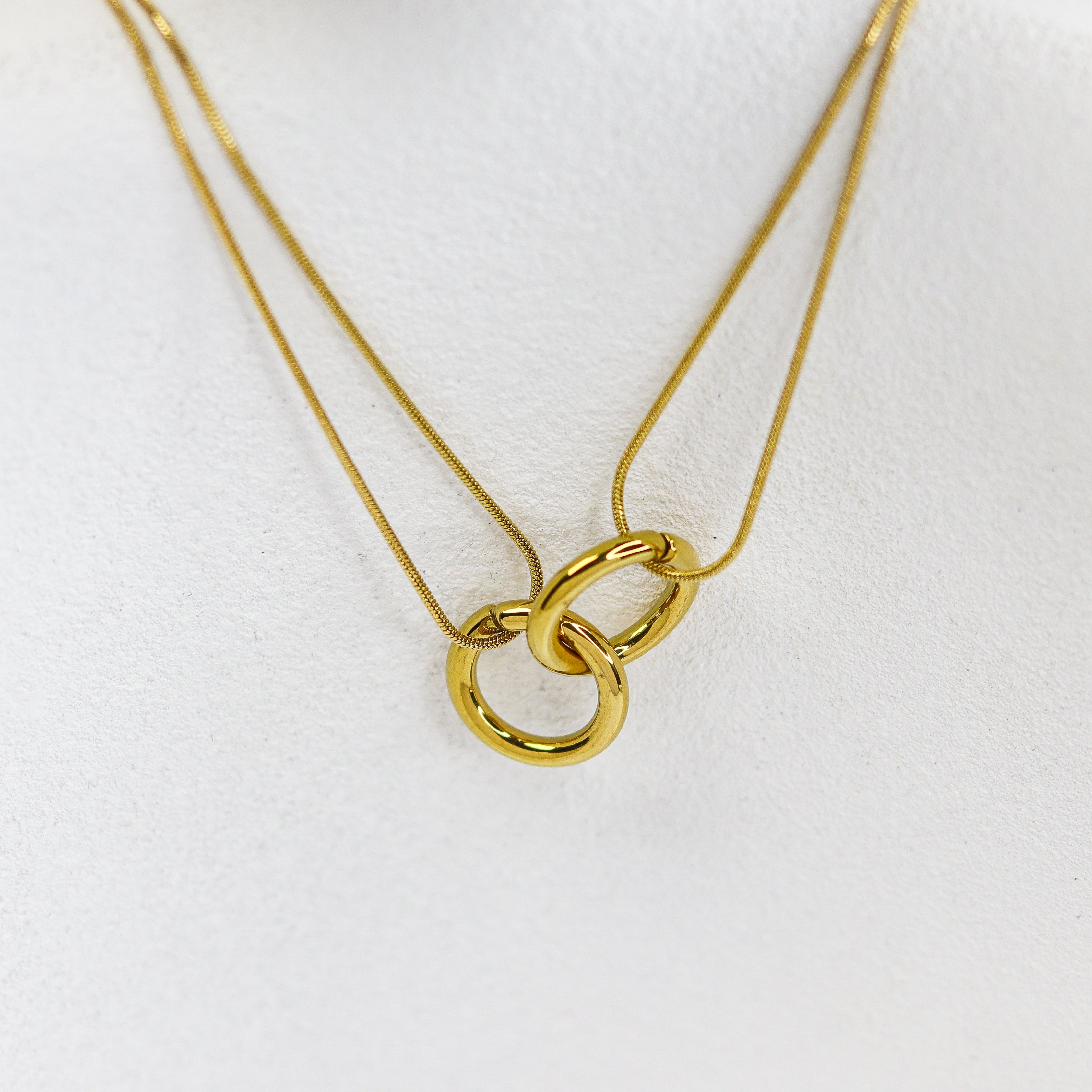 Gold necklace with interlocking rings on a white mannequin bust