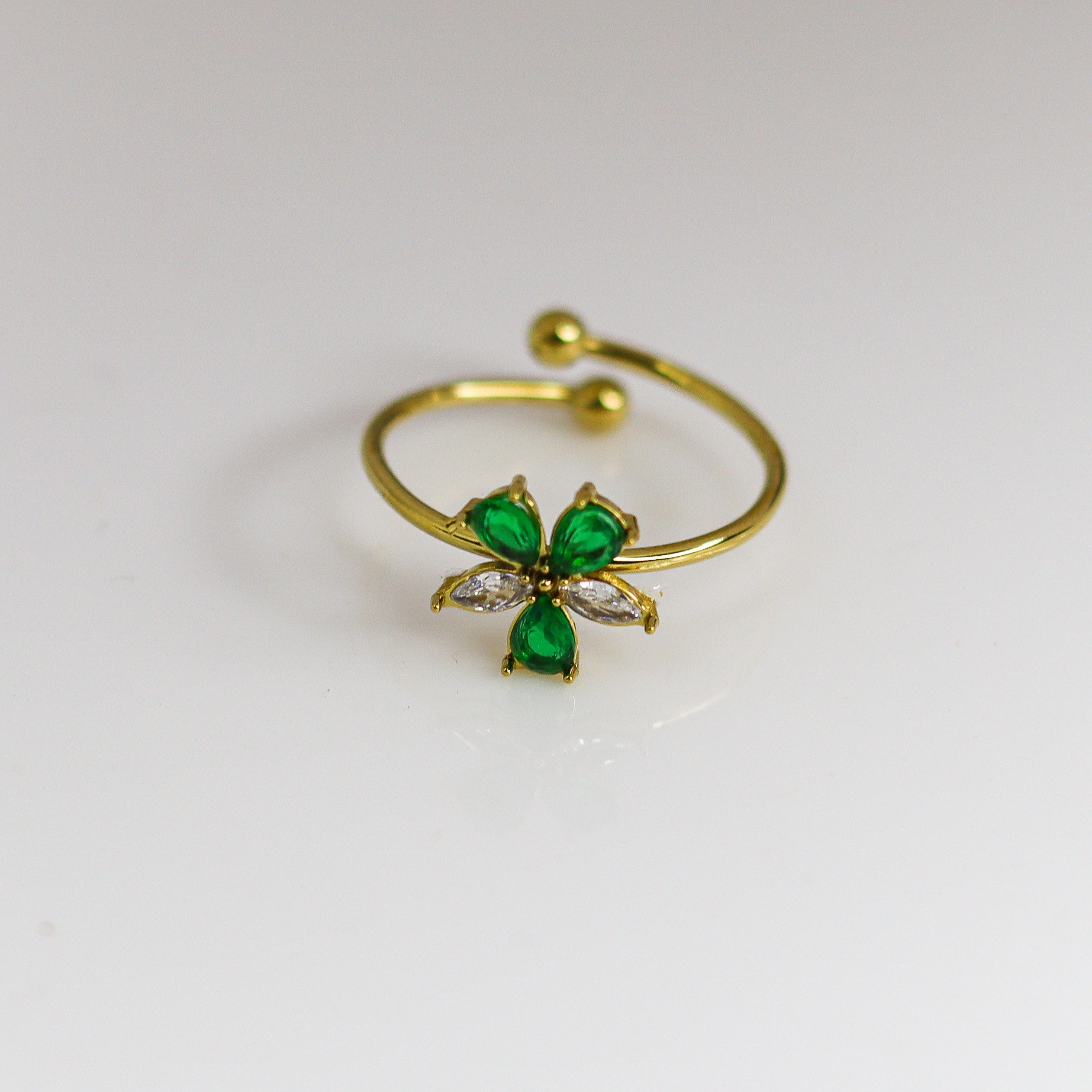 Gold ring with green gemstones on a white background