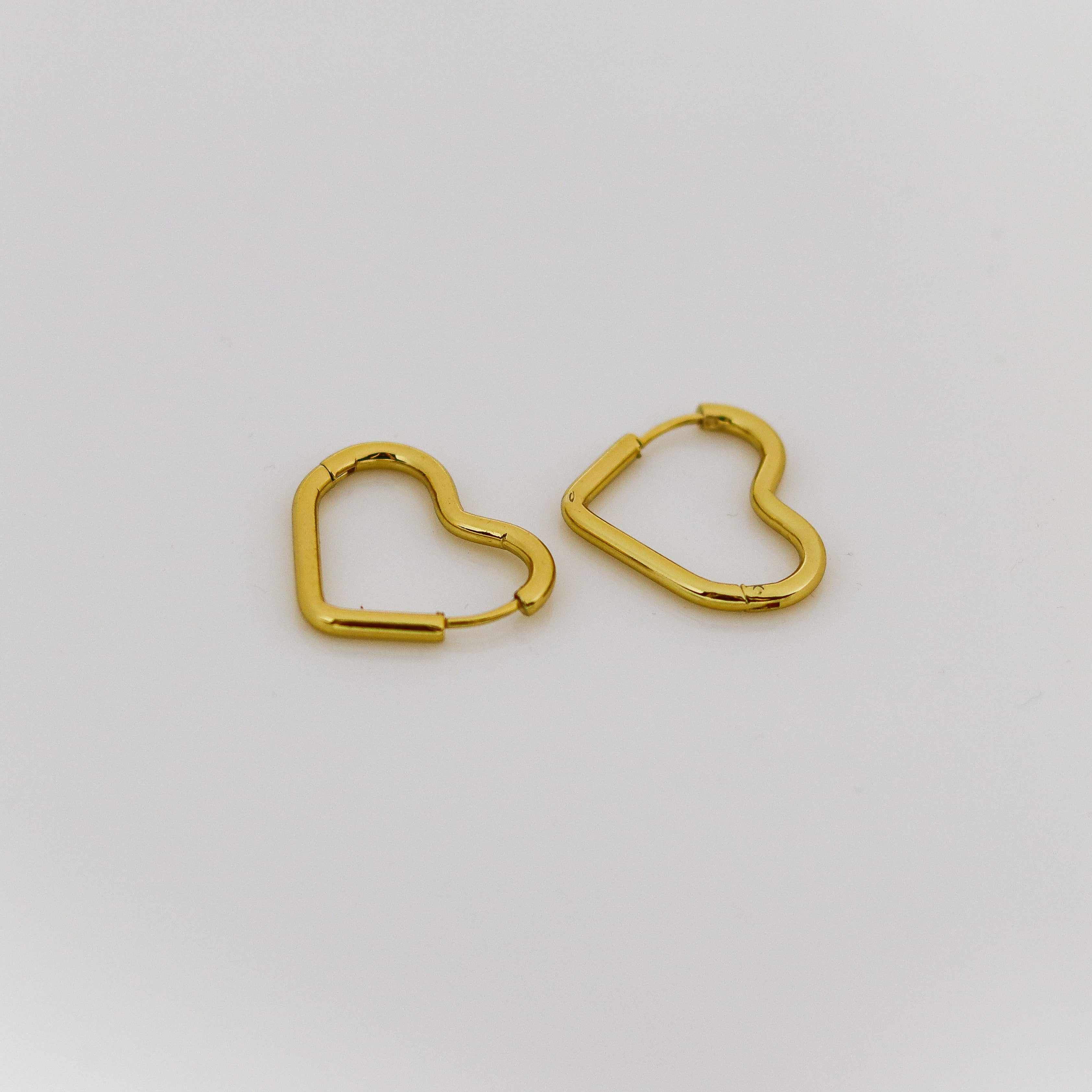 Gold heart-shaped earrings on a white background