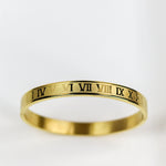 Gold ring with Roman numeral engraving on a white background