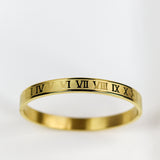 Gold ring with Roman numeral engraving on a white background
