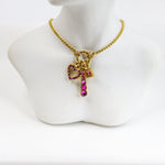 Gold necklace with a bow-shaped pendant and pink gemstones on a mannequin bust.