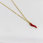 Gold necklace with a red chili pepper pendant on a white background