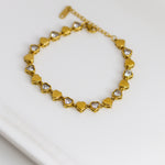Gold bracelet with heart-shaped links on a white surface