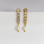 Gold earrings with crystal stones and pearls on a white background