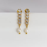 Gold earrings with crystal stones and pearls on a white background