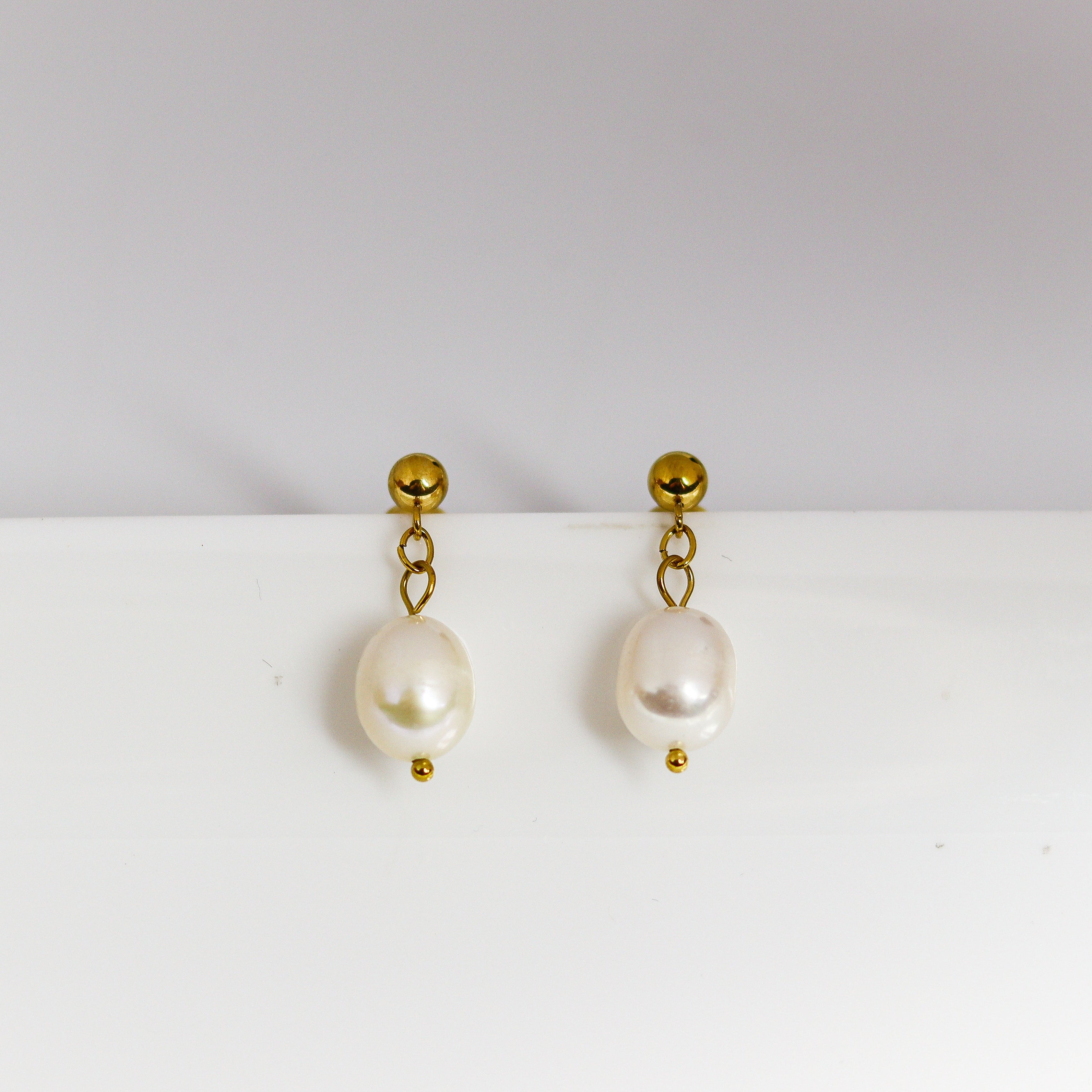 Pair of pearl earrings with gold hooks on a white background
