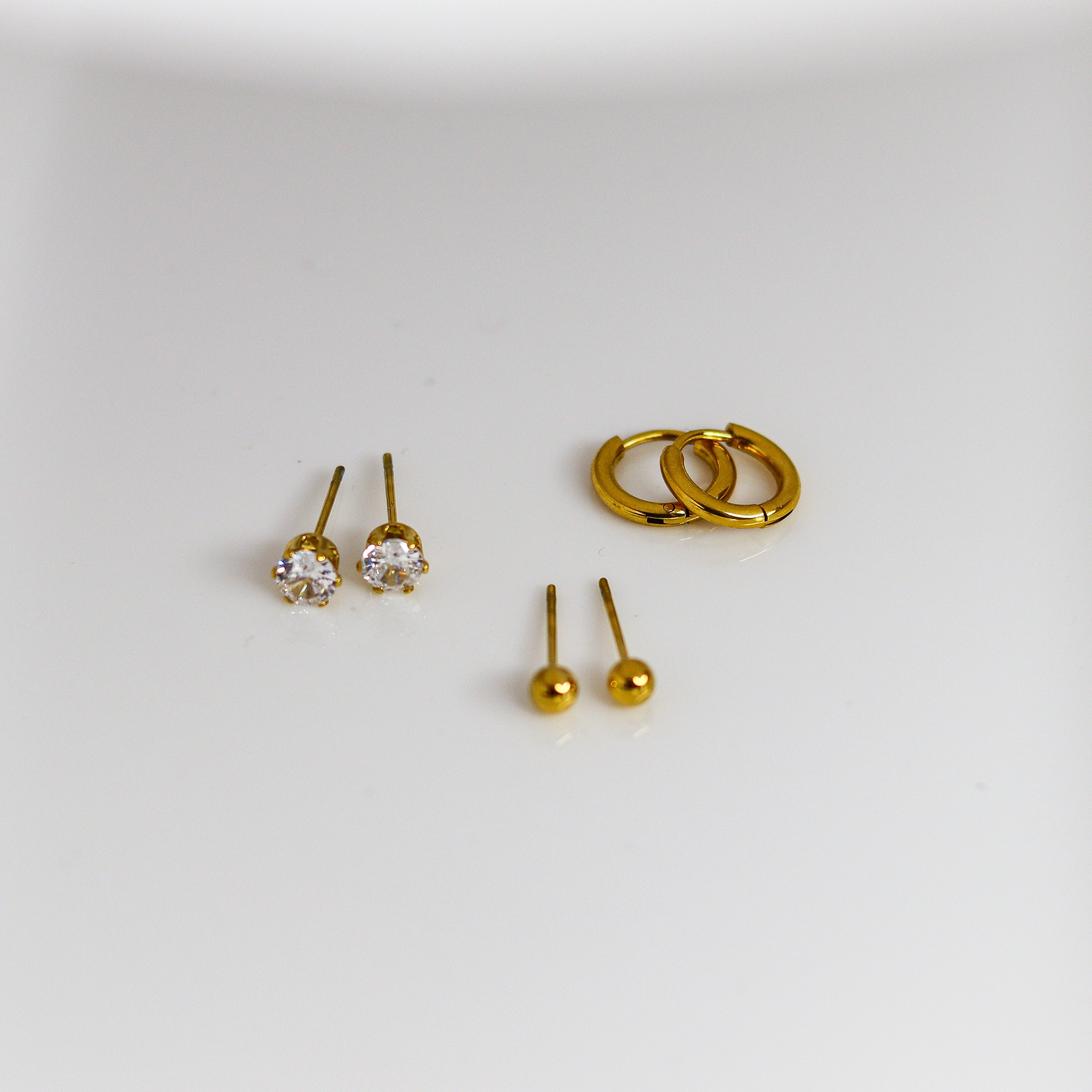 Gold earrings on a white surface