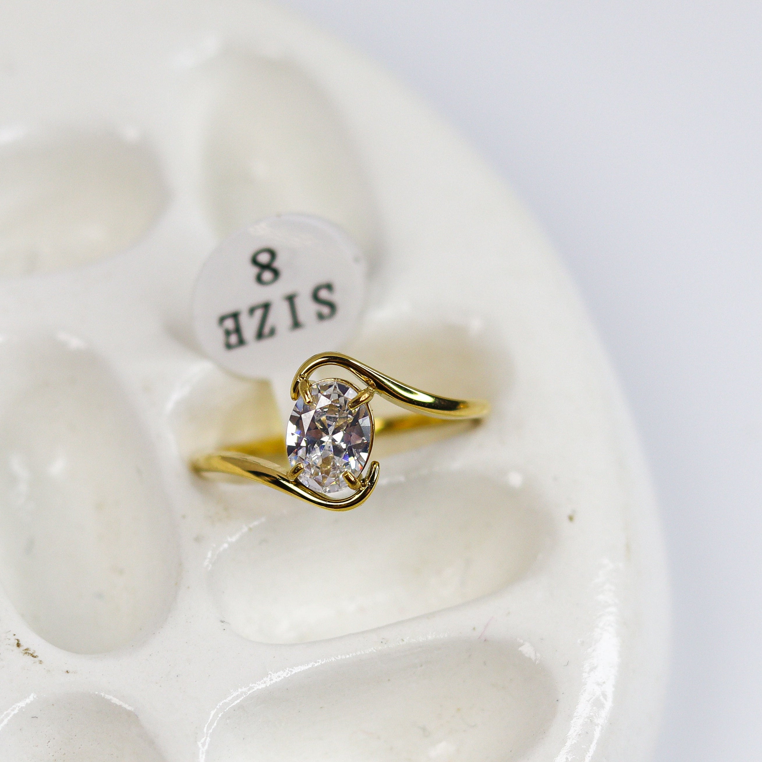 Gold ring with diamond on a white stone surface
