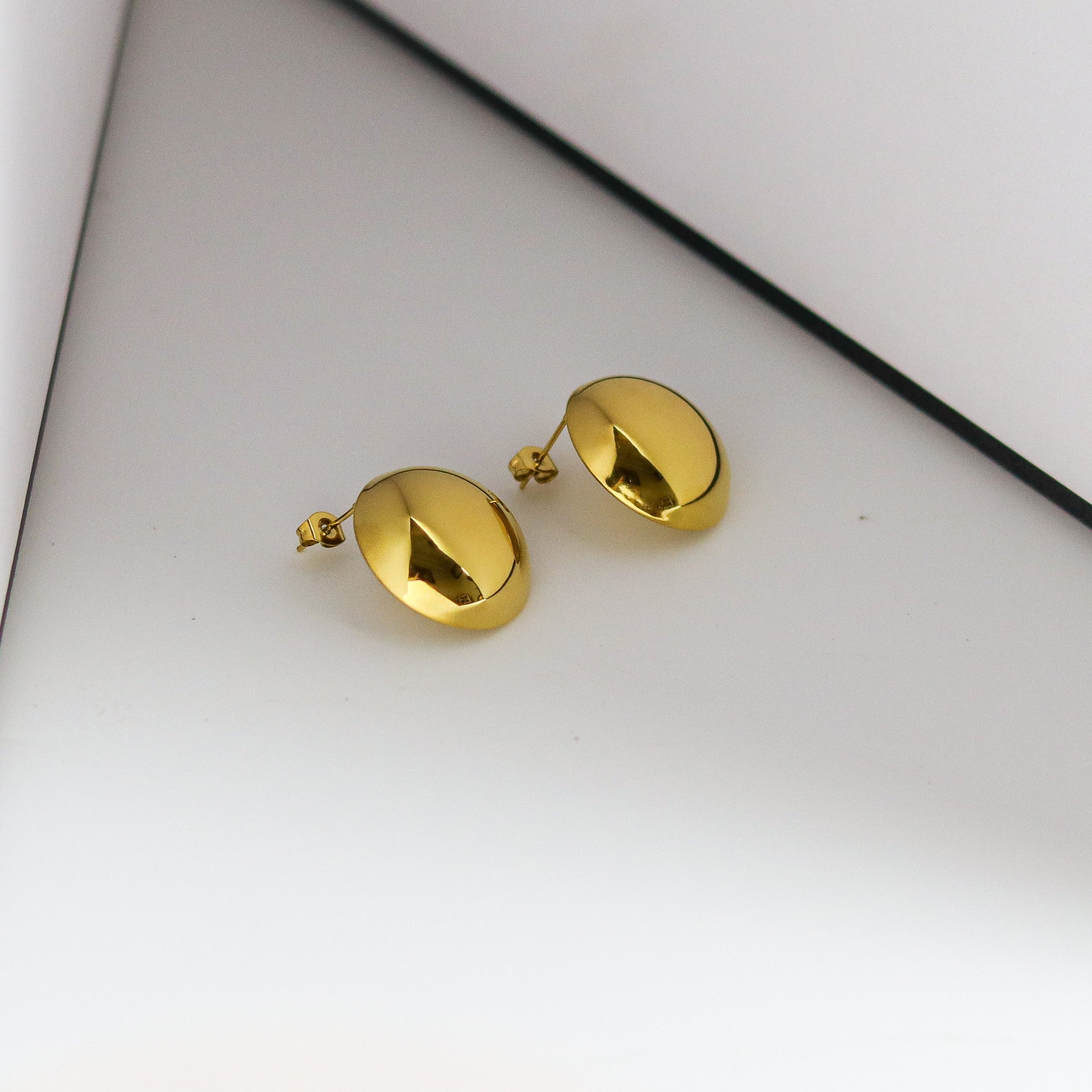 Gold bell-shaped earrings on a white background