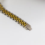 Metallic watch strap with yellow accents on a white background