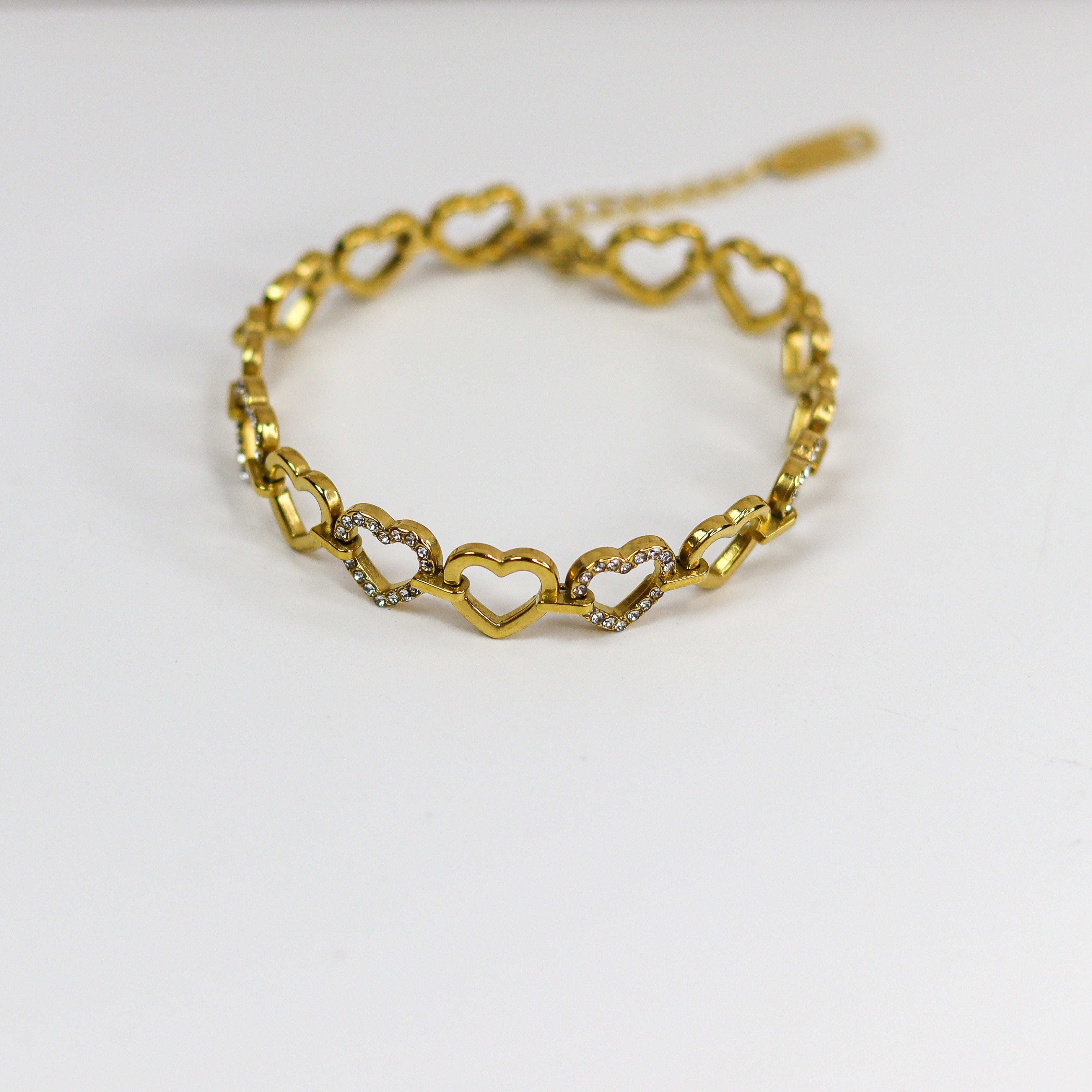 Gold bracelet with heart-shaped links on a white background
