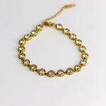 Gold bracelet with clear stones on a white background