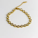 Gold bracelet with clear stones on a white background