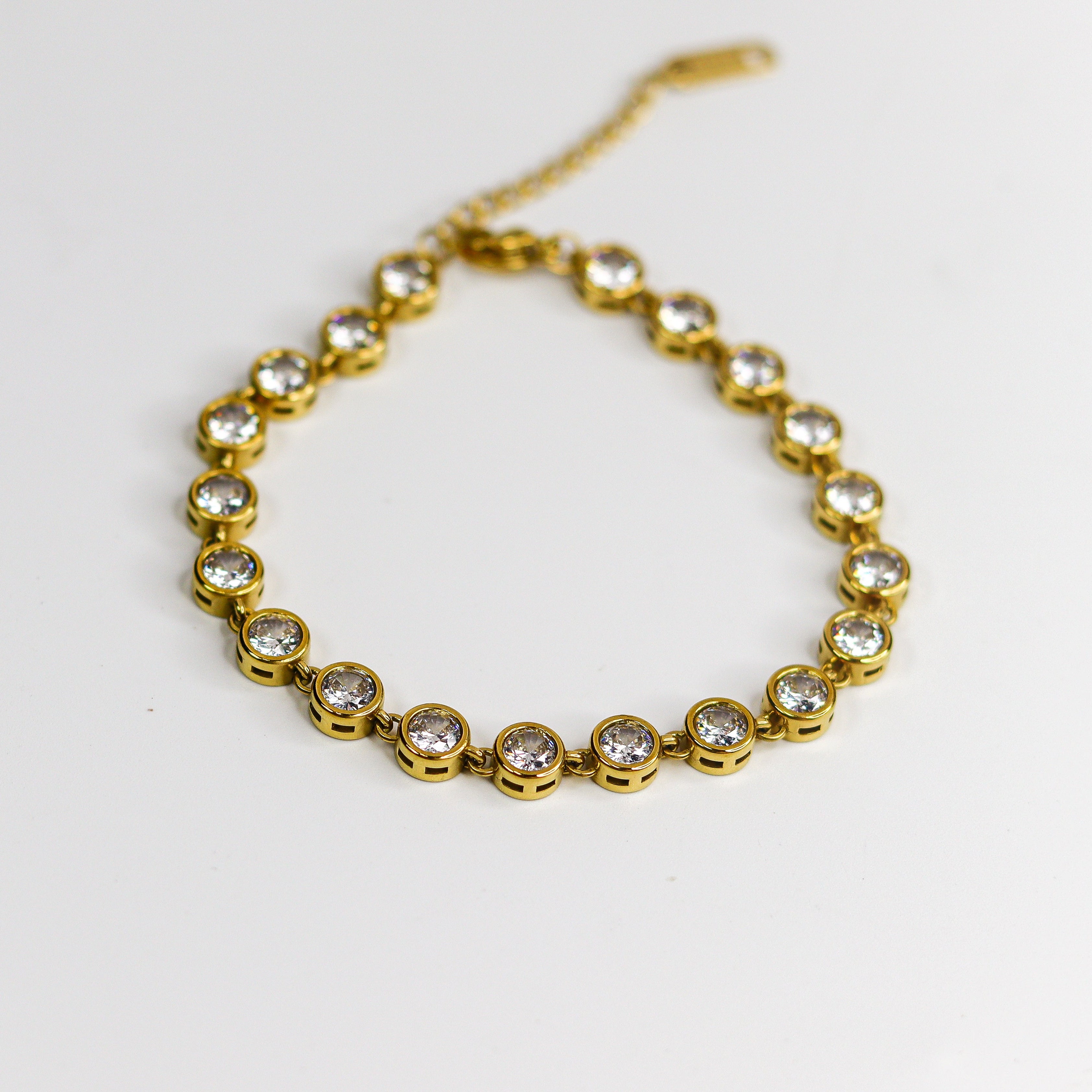 Gold bracelet with clear stones on a white background