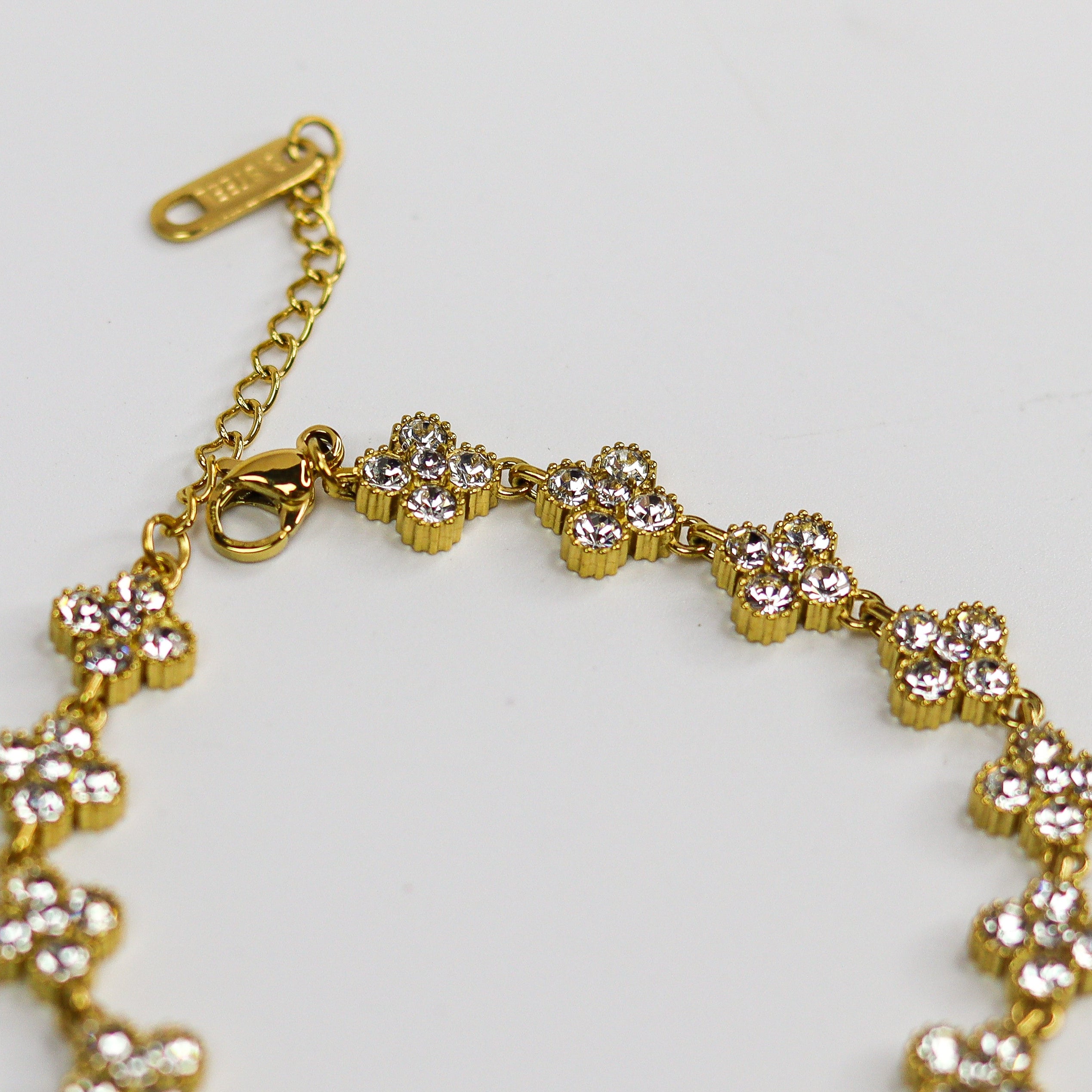 Gold bracelet with floral designs on a light gray background