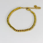Gold beaded bracelet on a white background
