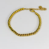 Gold beaded bracelet on a white background
