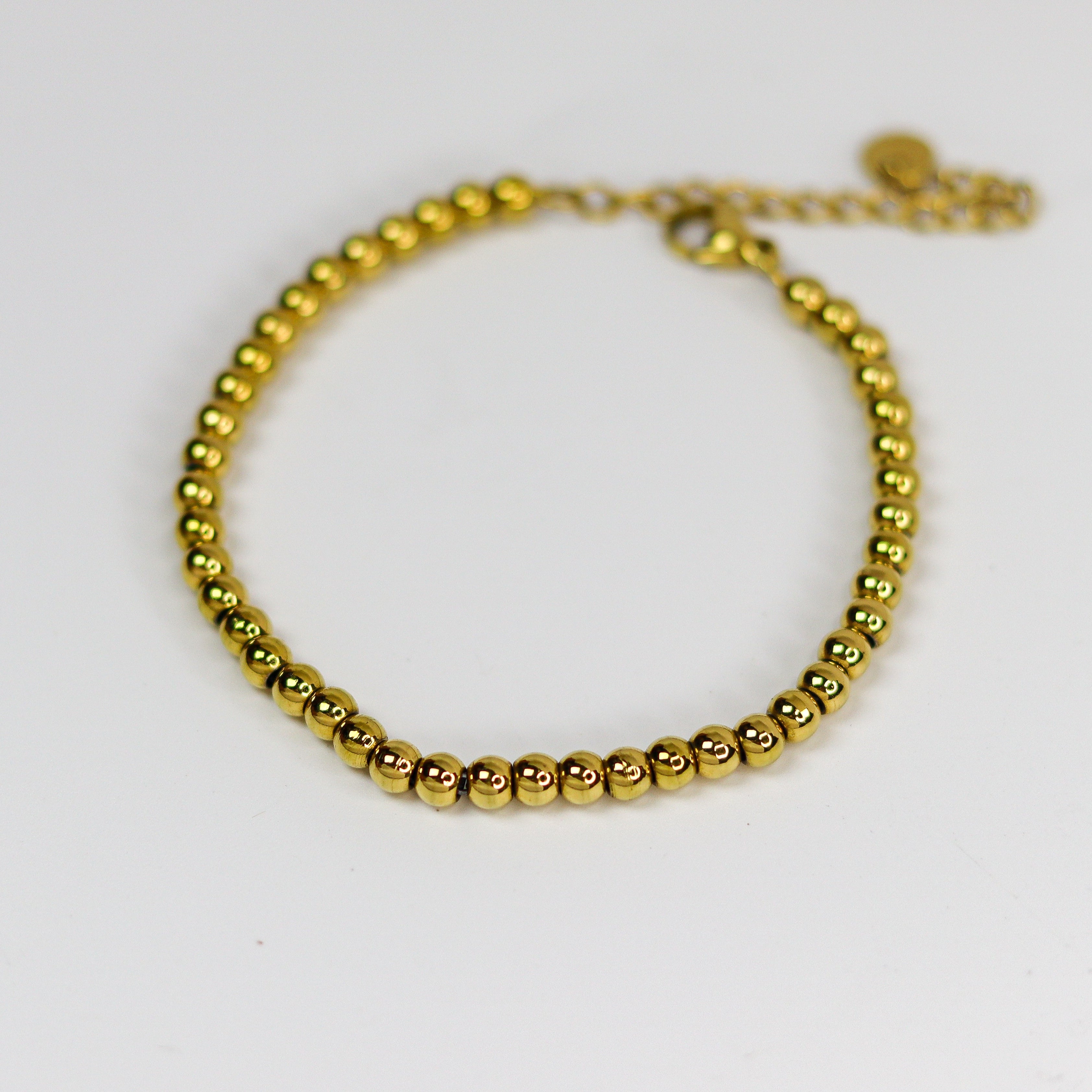 Gold beaded bracelet on a white background