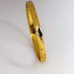 Gold bracelet with embedded stones on a light gray background