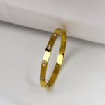 Gold bracelet with small diamonds on a light gray background
