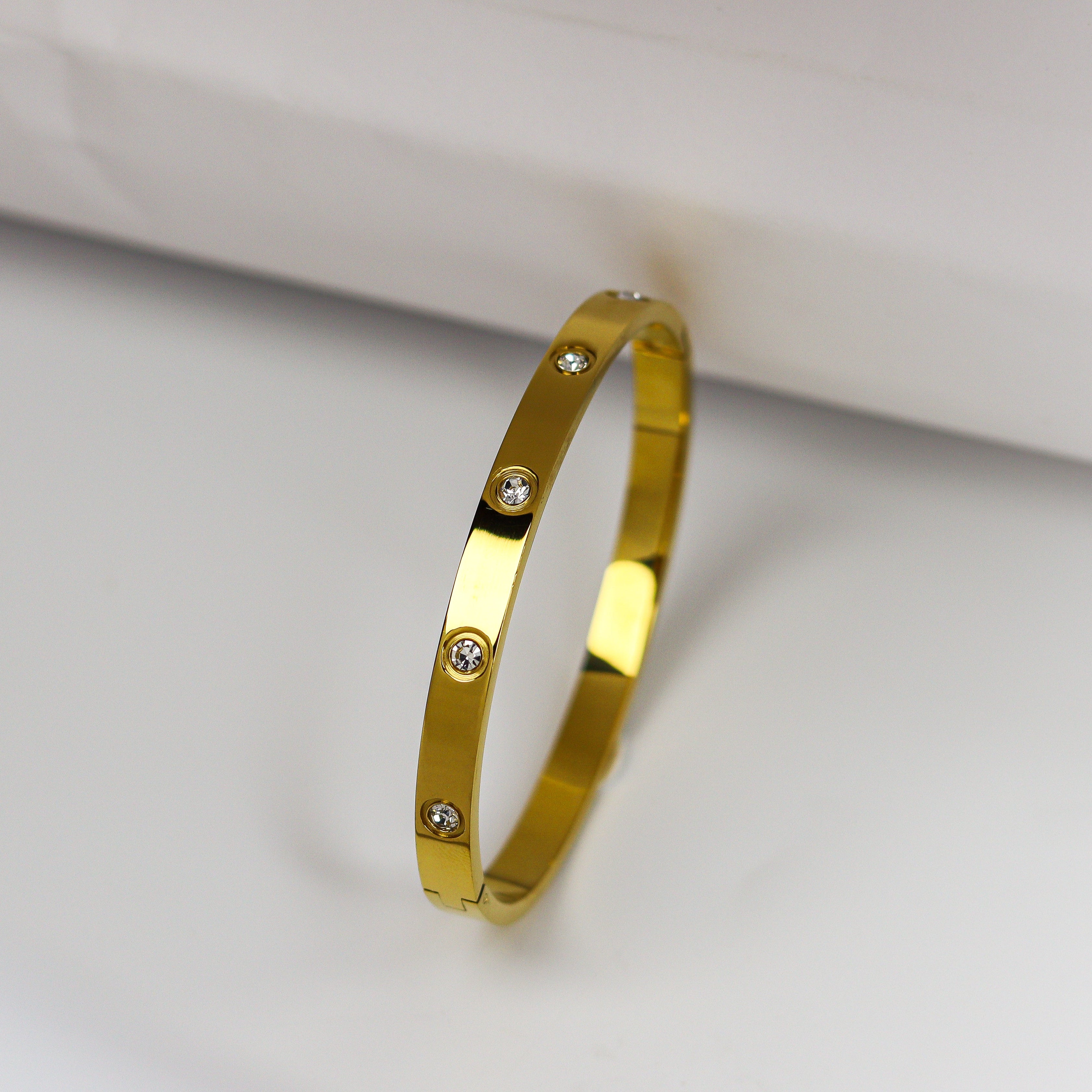 Gold bracelet with small diamonds on a light gray background