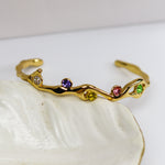 Gold bracelet with colorful stones on a white shell