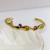 Gold bracelet with colorful stones on a white shell