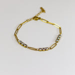Gold bracelet with small stones on a light gray background