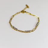 Gold bracelet with small stones on a light gray background