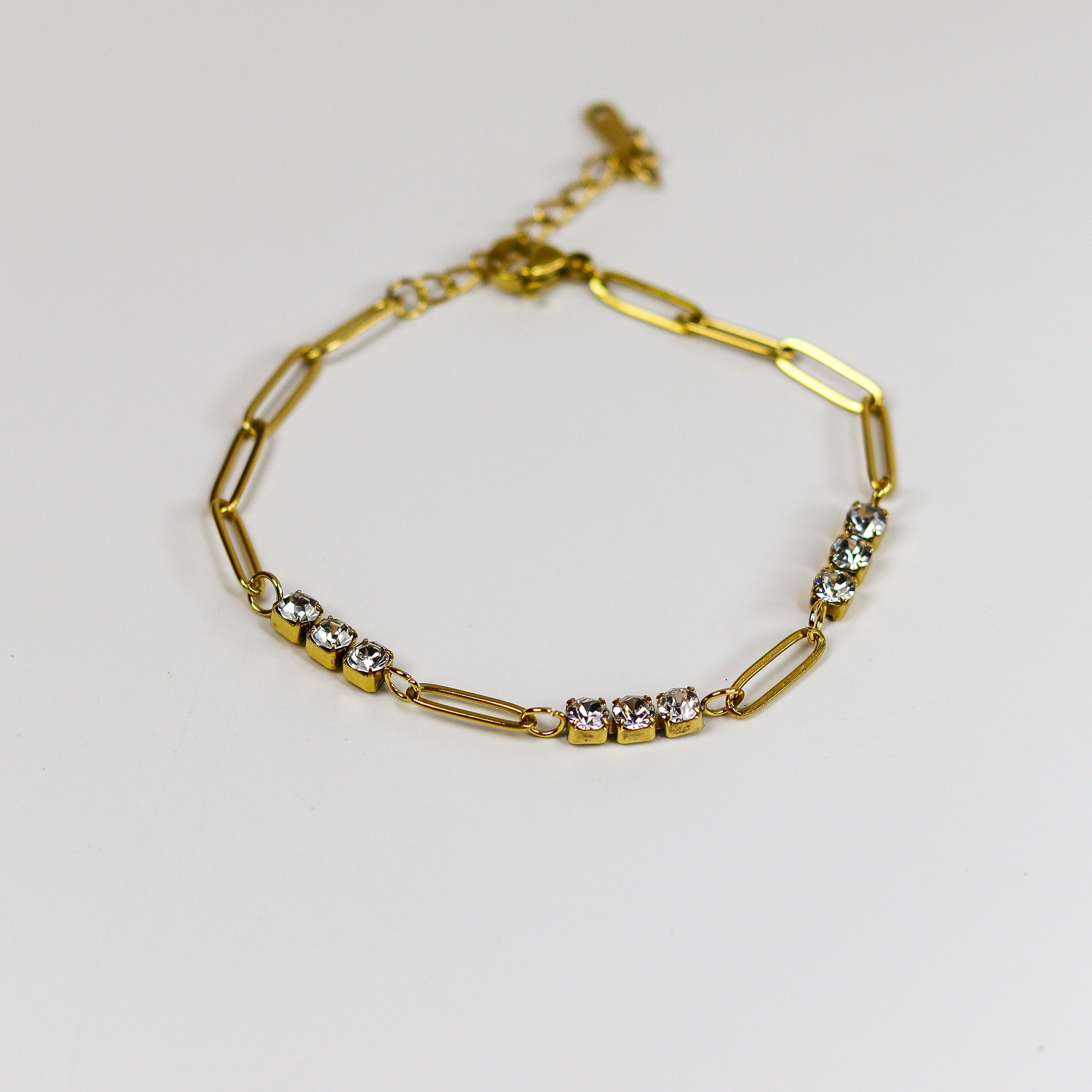 Gold bracelet with small stones on a light gray background