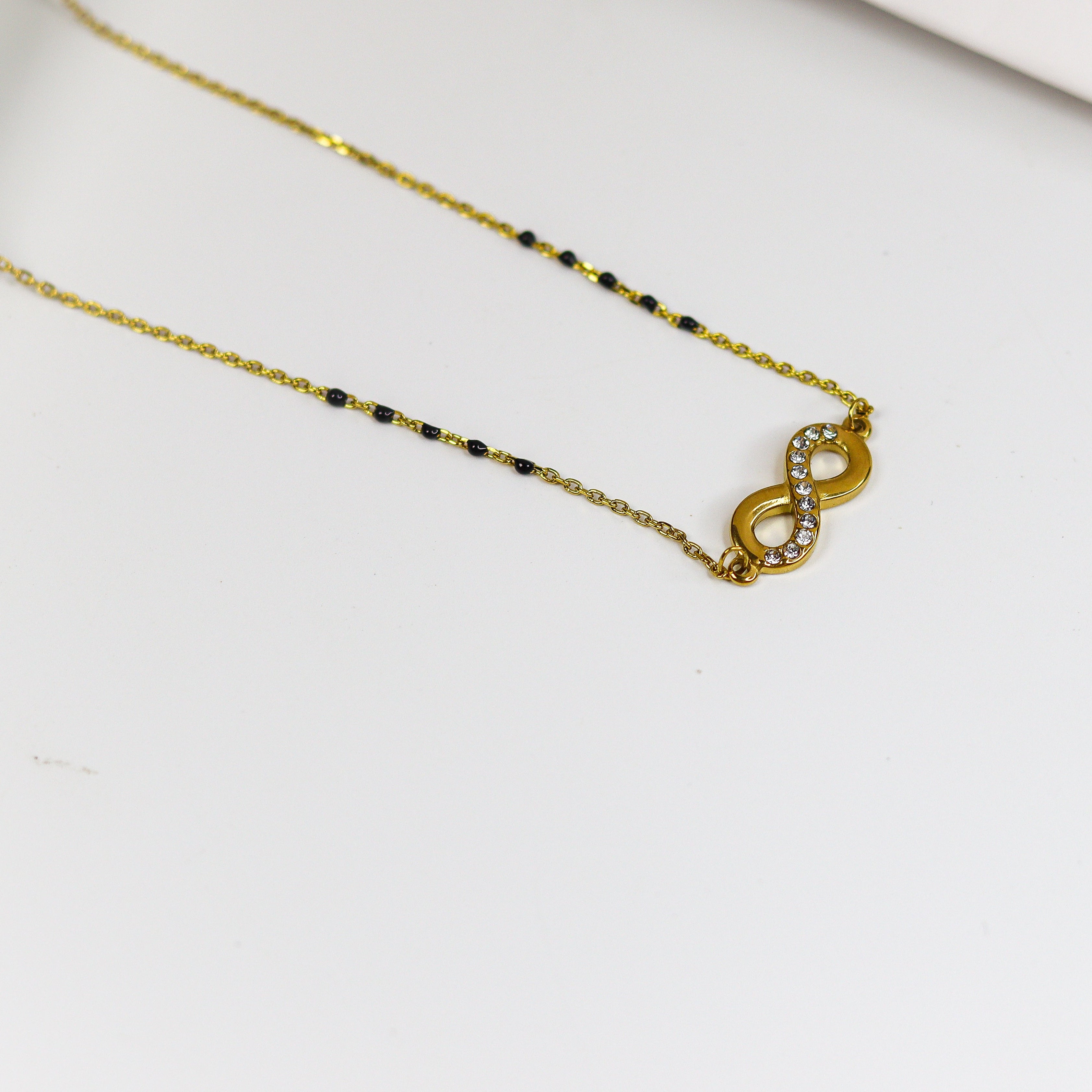 Gold necklace with a heart-shaped pendant on a white surface