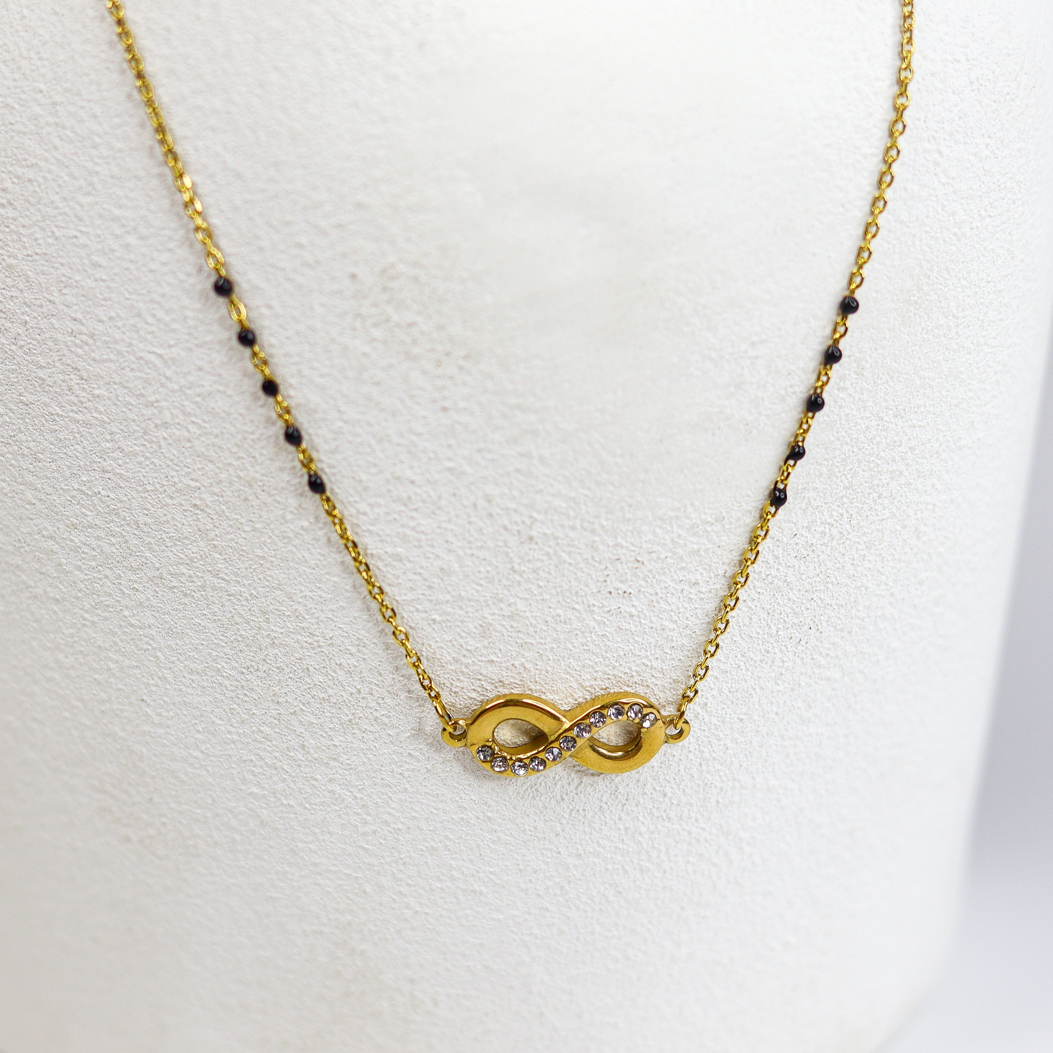 Gold infinity necklace on a white mannequin bust