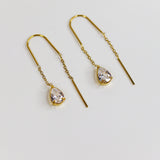 Gold earrings with teardrop-shaped gemstones on a light gray background