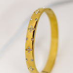 Gold bracelet with small diamonds on a light gray background